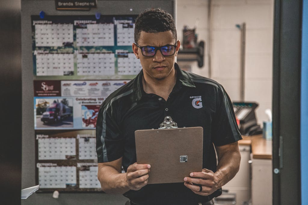 A serious worker in a warehouse checks documents on a clipboard, planning and logistics.