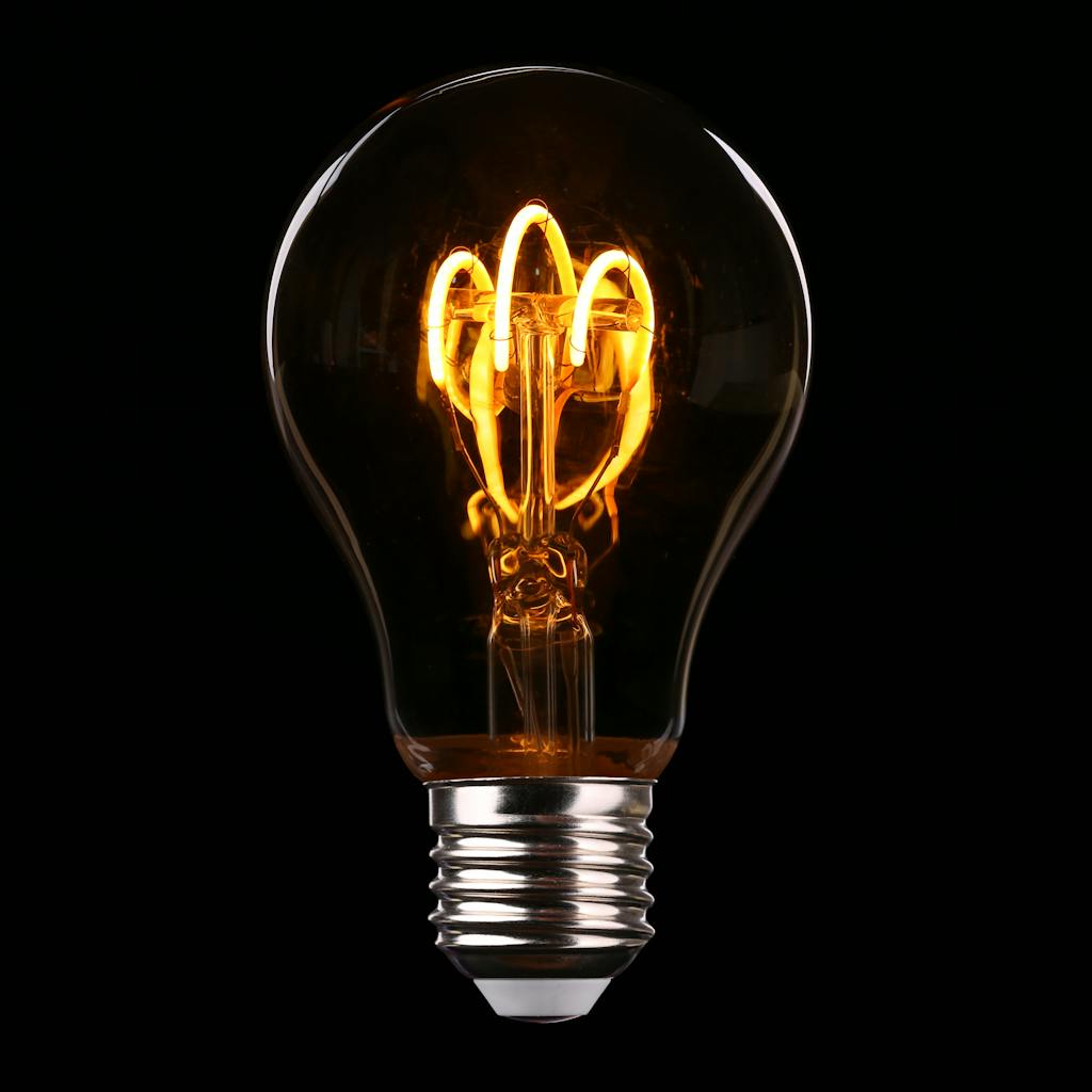 Close-up of an illuminated Edison-style light bulb on a dark background.